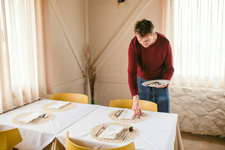 Camarero colocando cubiertos en mesa de restaurante